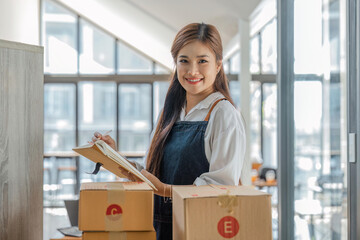 Business From Home Asian woman preparing package delivery box Shipping for shopping online. young...