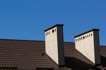 Fototapeta na wymiar Metal roof of a detached house and chimney against the sky, metal roof tiles, gutters
