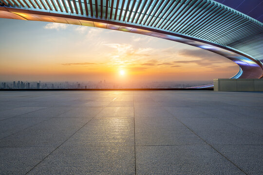 Empty square floor and bridge with city skyline at sunset
