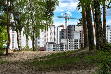 Fototapeta premium New highrises district with a constuction crain on the edge of woodland