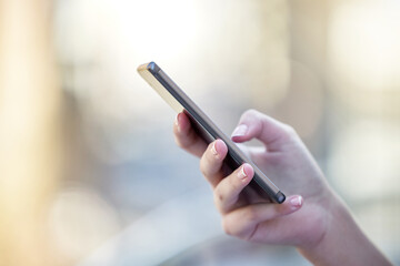 Hand, phone and communication with a woman typing a text message closeup on a blurred background. Mobile, contact and social media with a female person reading a text or networking alone outdoor