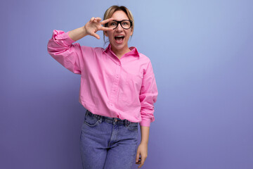 young cute friendly blond european woman model with ponytail hairstyle in stylish look consisting of pink shirt and denim pants