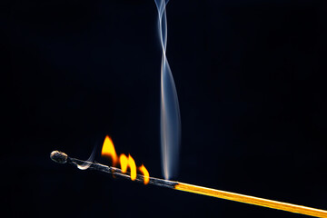 Flashed and burning wooden match on a dark background close-up. Bright fire and smoke from a...
