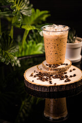 iced cappuccino coffee In a glass ready to serve Beautifully decorated with green leaves and coffee beans on a black background.
