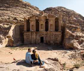 Traveler couple observing the Ad Deir - Monastery in the ancient city of Petra, famous travel...
