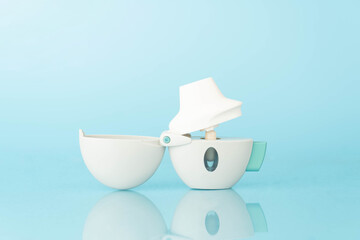 Asthma and COPD concept. Tiotropium bromide inhaler with reflection on light blue background. Pharmaceutical device of bronchodilator for lung inflammation treatment and prevent asthma attack.