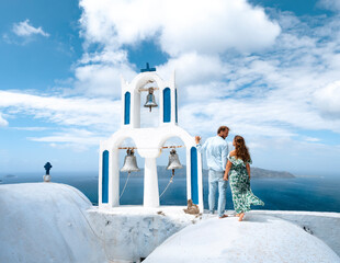 Young traveler couple on honeymoon enjoying the sights of Oia on the island of Santorini in Greece - obrazy, fototapety, plakaty