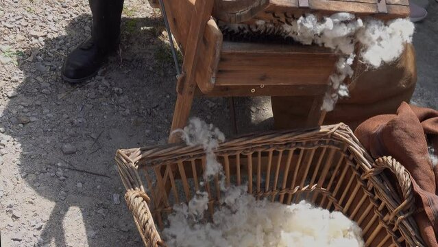 processing sheep wool on an old wooden machine.