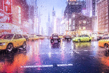 View through a glass window with raindrops on city streets with cars in the rain, bokeh of colorful city lights, night street scene. Focus on ra