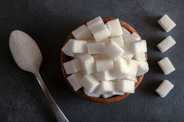 Cube sugar and granulated sugar on black background
