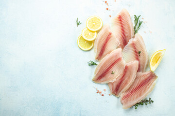 Raw fillet of telapia or pangasius with lemon and spices on a light background. banner, menu,...