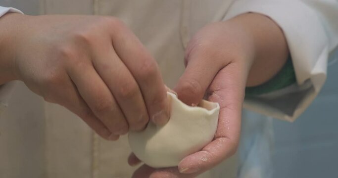 close up chef hand make and wrap Chinese Baozi (stuffed bun). Traditional Chinese food