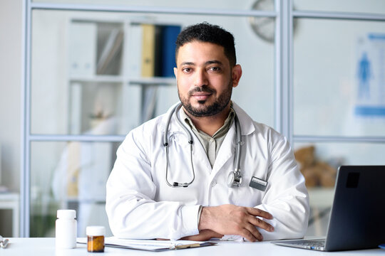 Portrait of professional doctor looking at camera while sitting at his workplace in office