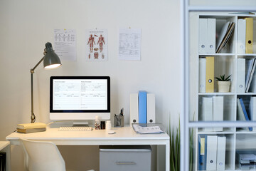 Modern office of doctor with workplace with computer on table and posters on the wall