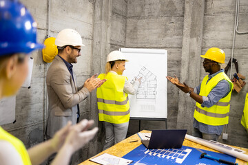 Motivated and positive group of structural engineers at construction site meeting laughing and clapping hands. - obrazy, fototapety, plakaty