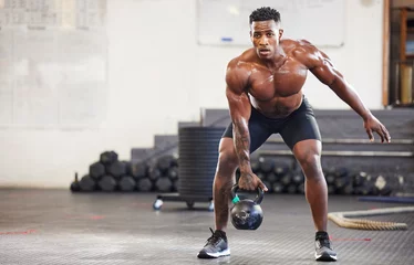 Deurstickers Fitness Black man, fitness and weightlifting with kettlebell for workout, exercise or training at the gym. African male person or muscular bodybuilder lifting weight for strength sports or intense exercising