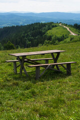 Wooden table for picnics, and benches among greenery high in the mountains in summer.