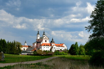 Fototapeta na wymiar A view of an old monastery used to train and house monks and priests protected by a strong red brick and concrete wall and located next to a massive moat seen in Poland in summer