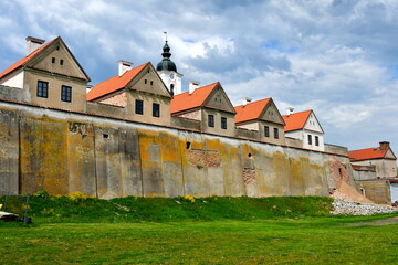 A view of an old monastery used to train and house monks and priests protected by a strong red brick and concrete wall and located next to a massive moat seen in Poland in summer