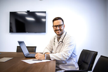 Portrait of young experienced doctor working on the computer in clinic office.