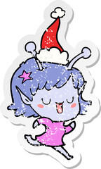 happy alien girl hand drawn distressed sticker cartoon of a wearing santa hat