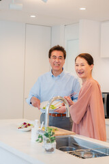 キッチンで一緒にクッキングを楽しむシニアの夫婦