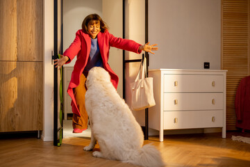 Dog meets its owner at the doorway of living room at home. Concept of a happy homecoming when your...