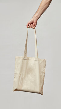 Cloth bag in hand on light background. Bag shoper in the hand