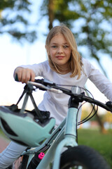 Fototapeta na wymiar Portrait of a cute baby girl on a bike in the park, vertically.