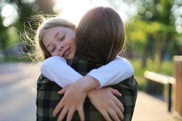 Happy daughter hugging mom in the park, love, human relationships.