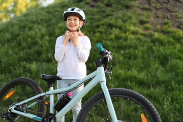 Child girl wears helmet, safe bike ride.