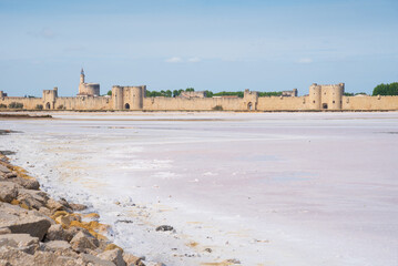 Pink salt marshes landscape near Aigues-Mortes, France. Medieval town of  Aigues Mortes with its...