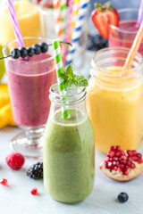 Fresh fruit smoothies with colourful straws surrounded by fresh fruit.