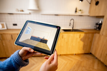 Designing kitchen space with a digital tablet. Holding touchpad with running program of kitchen project on background of real interior. Concept of interior design and modern technologies