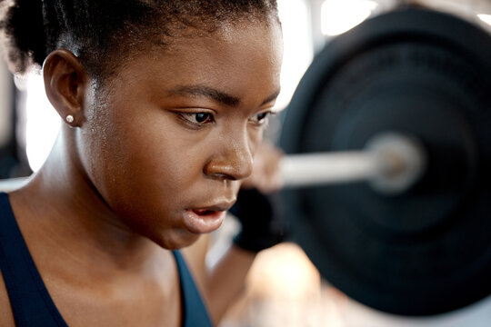 Closeup, weightlifting and barbell with black woman in gym for workout, strong and muscle. Health, challenge and exercise with female bodybuilder and weights for focus, performance and commitment