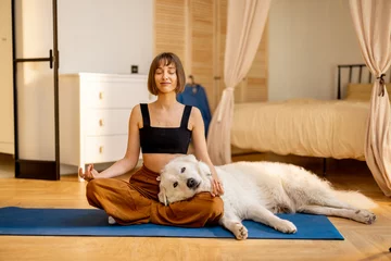 Poster Young woman cares her cute dog, hugs together while doing yoga at home. Concept of dog therapy and mental health © rh2010