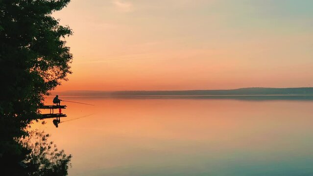 Side view of a fisherman on the pond. Fishing at sunset. Russian fisherman with fishing rods on the background of a pond and a golden sunset. Russia, Votkinsk