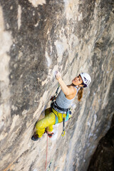woman climbing big walls in the mountains, doing sports, striving hard for her goals without fear of success, courageous person, confident person with commitment.