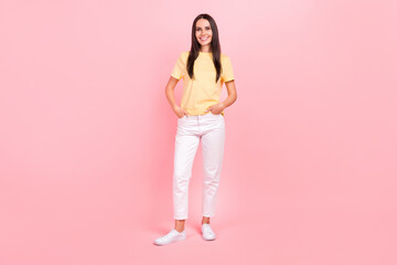 Fototapeta na wymiar Full length photo of shiny adorable lady wear yellow t-shirt walking arms pockets isolated pink color background