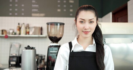 Portrait of attractive young beautiful asian women barista in apron smiling and looking at camera in coffee shop counter. Coffee business owner concept