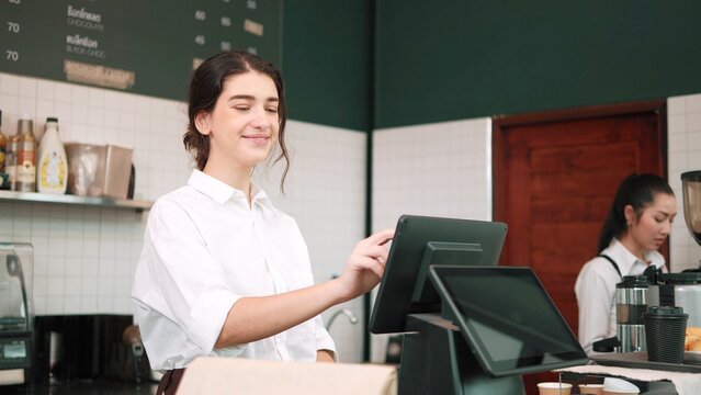 Smiling woman barista using computer take order from customer in coffee shop. Coffee business concept