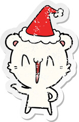 laughing polar bear hand drawn distressed sticker cartoon of a wearing santa hat