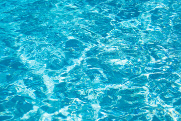 Fototapeta na wymiar Water background, ripple waves. Blue swiming pool pattern. Sea surface. Water in swimming pool with sun reflection. Banner with copy space.