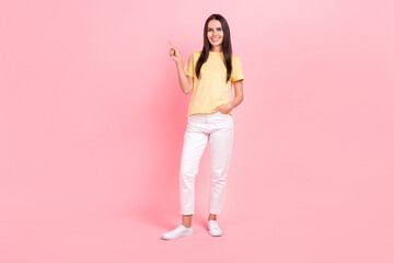 Fototapeta na wymiar Full length photo of adorable pretty lady wear yellow t-shirt pointing finger empty space isolated pink color background