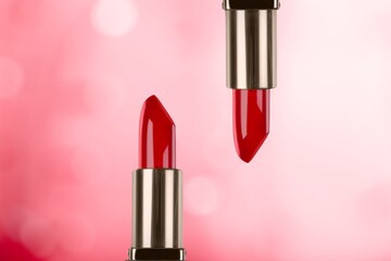 Two beautiful red lipsticks on a color background