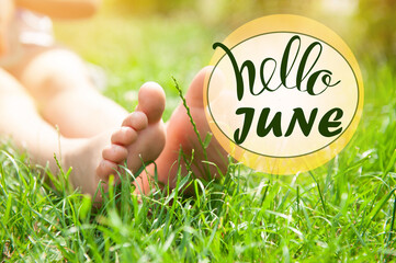 Hello June. Child sitting barefoot in green grass on sunny day, closeup © New Africa