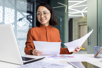 Young successful asian financier behind paper work inside office, businesswoman accountant...
