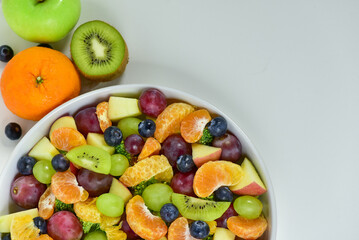 Healthy fresh fruit salad bowl on white background. Top view. Healthy food concept, healthy high vitamin fruit, mixed fruit background.
