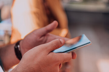 Closeup photo of businessman hand utilizes his smartphone outdoors, showcasing the seamless integration of technology and mobility in modern professional life.