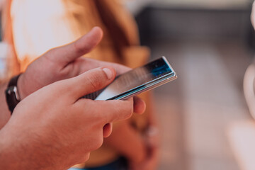 Closeup photo of businessman hand utilizes his smartphone outdoors, showcasing the seamless integration of technology and mobility in modern professional life.